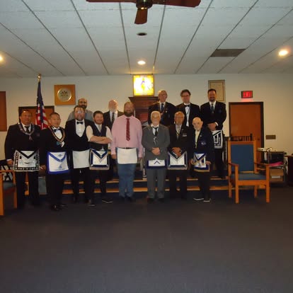 Lodge officers in aprons and regalia standing together in the lodge room after a ceremony